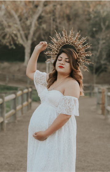 Maternity photoshoot. Mother posing holding belly and wearing golden radiant crown.